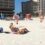 Friends perform synchronised back flips on a beach